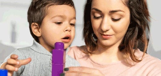 A woman and a young child play with purple building blocks.