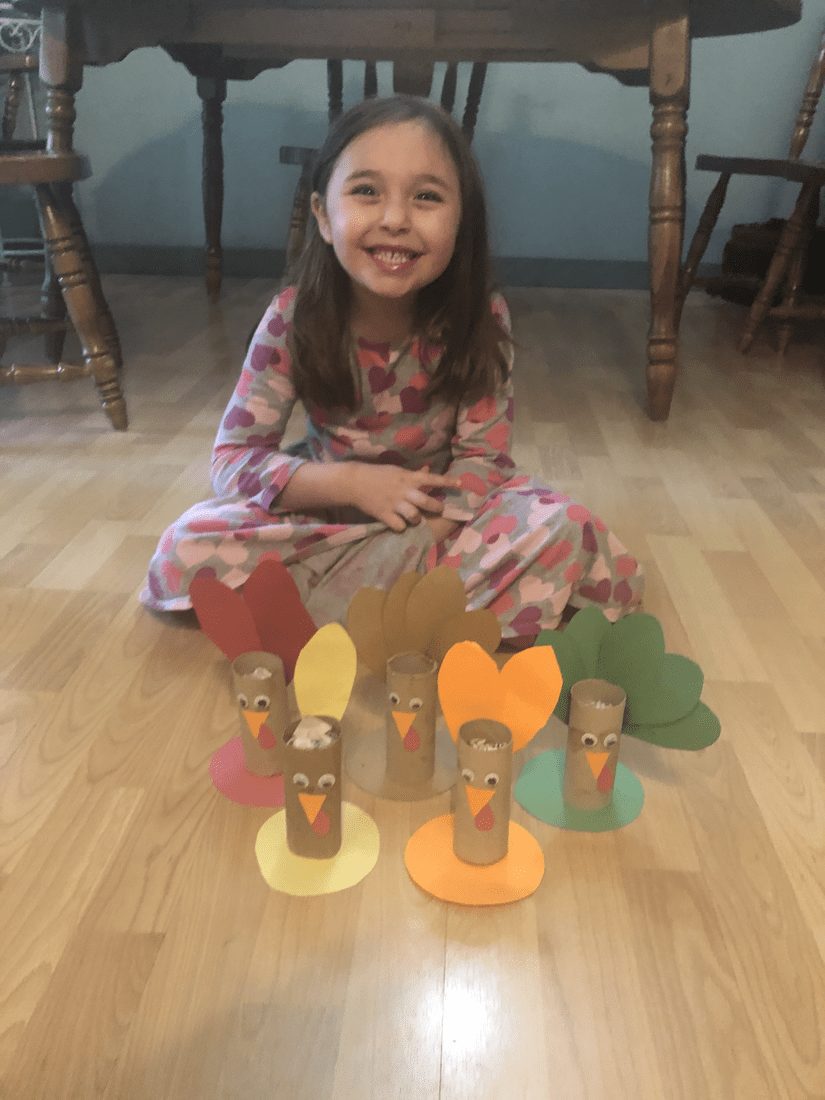 Girl sitting on the floor with turkey crafts