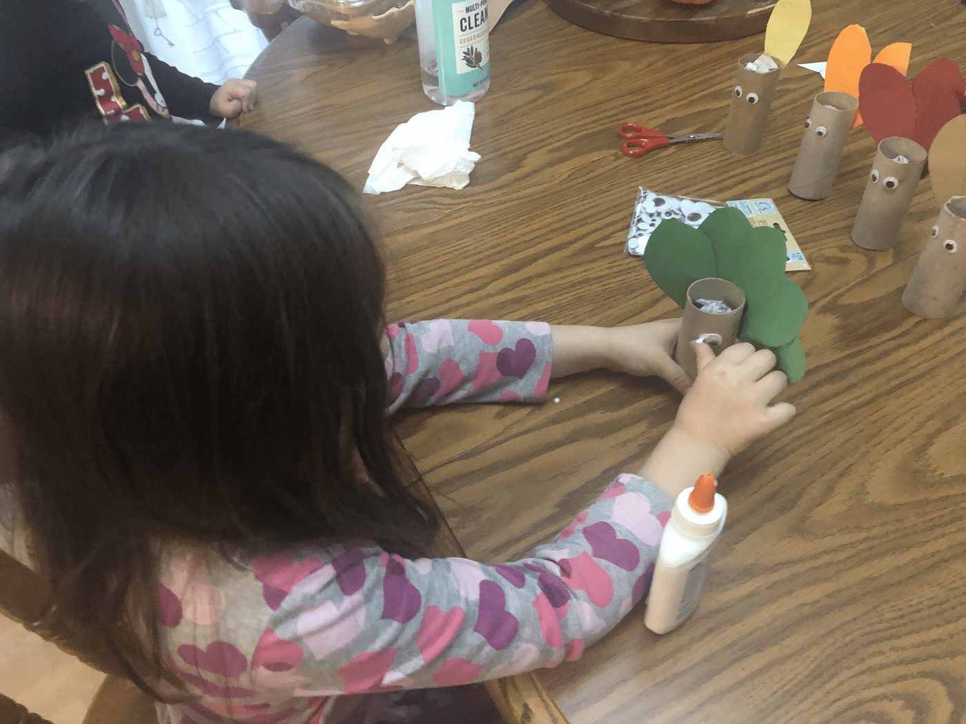 Child crafting turkey bowling pins from toilet paper tubes and paper.