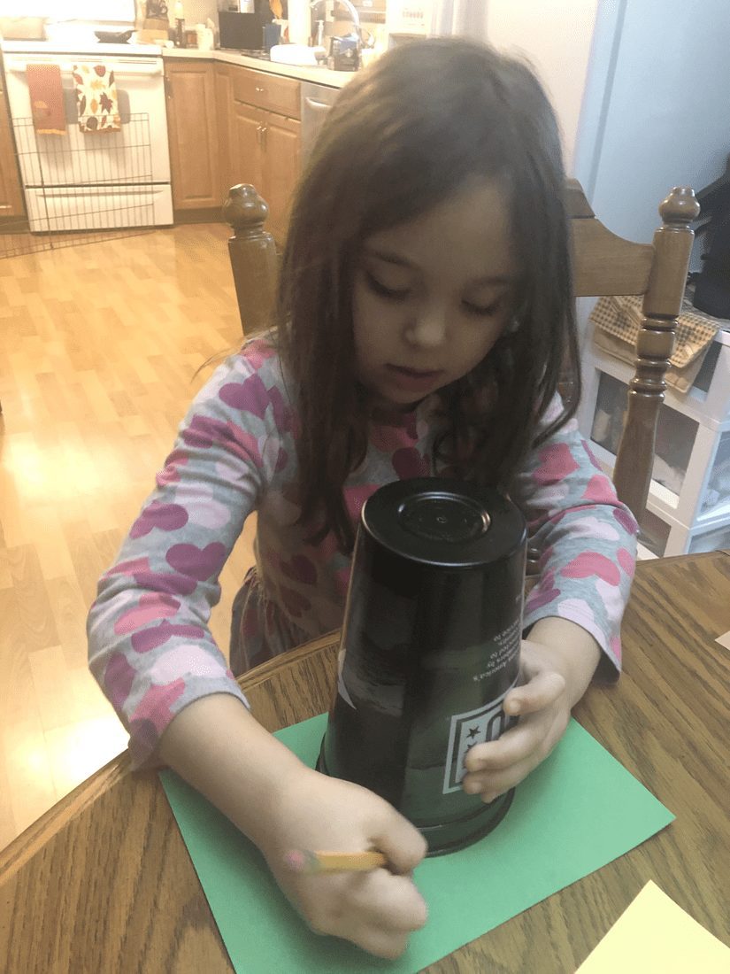 Young girl decorating a toilet paper tube for turkey bowling.