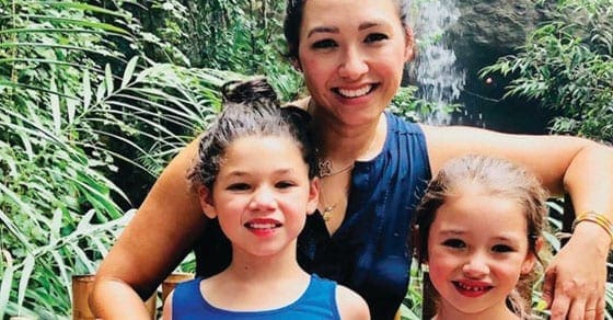 Lisa Pena with two children in front of lush greenery and a waterfall.