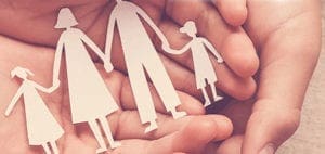 Paper cutout of a family held in cupped hands.