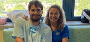 A man wearing a blue shirt with a name tag and a woman with curly hair smiling at the camera.