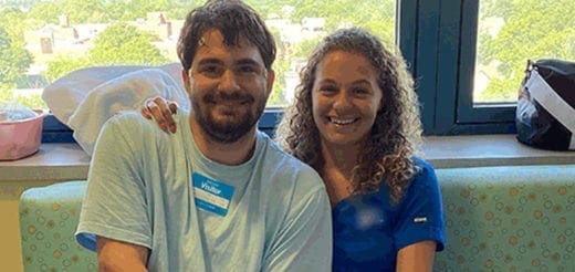 A man wearing a blue shirt with a name tag and a woman with curly hair smiling at the camera.