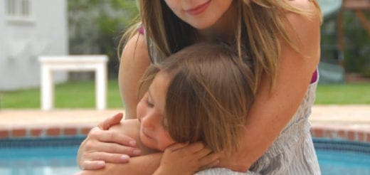 Woman hugging a child by a pool.