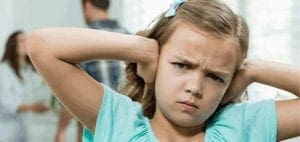 A child covers her ears with a distressed expression as two adults argue in the background.