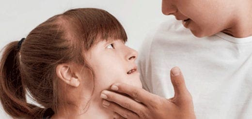 A child looks up at an adult who is touching their face.