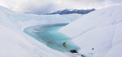 A kayaker paddles through a turquoise pool on the Matanuska Glacier in Alaska.