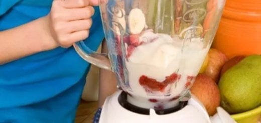 Blender with strawberries, banana slices, and ice for a smoothie