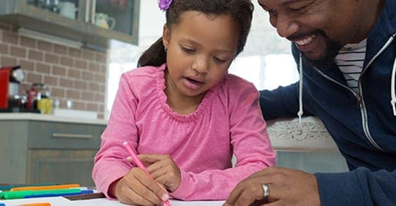 Father and daughter working on homework at a table.