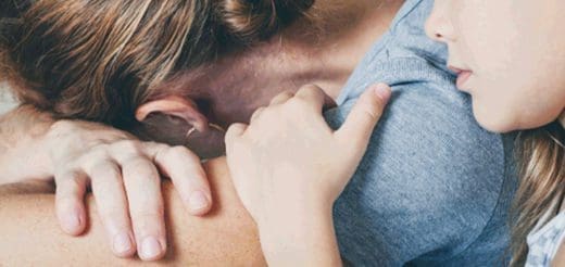 Child's hand rests on an adult's shoulder.