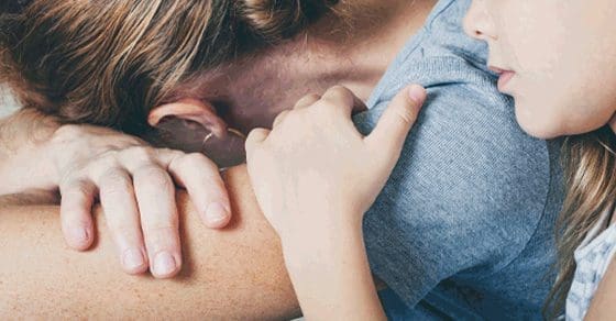 A child hugs an adult from behind.