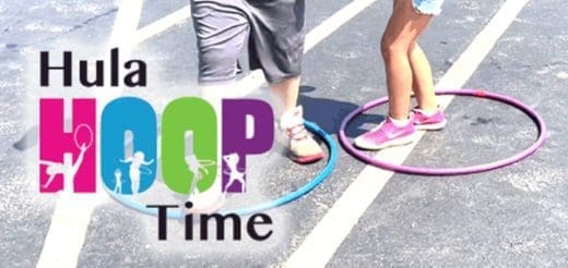 Two people are hula hooping on a paved surface.