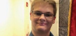 Young person with glasses smiling.