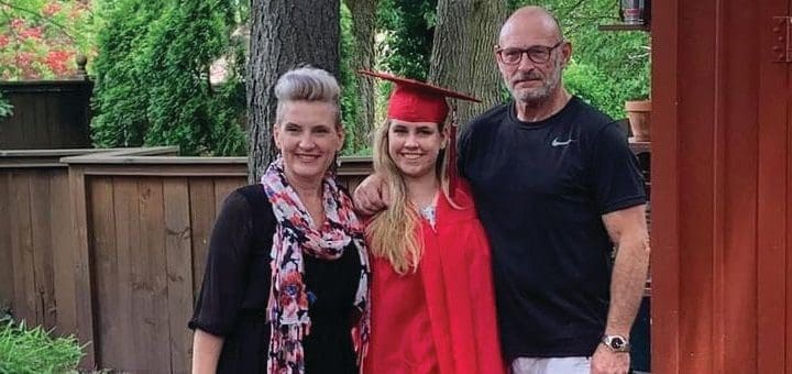 Millicent Nicole Huser with two adults celebrating graduation