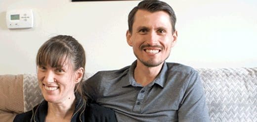 Sarah and Eric smiling while sitting on a couch.