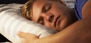 A man sleeps soundly on a striped pillow.