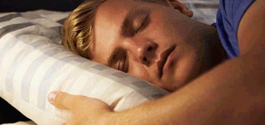A man sleeps soundly on a striped pillow.