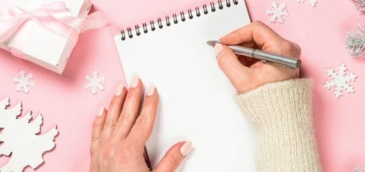 Hands writing on a blank notepad surrounded by festive decorations.