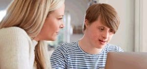 Woman and young man with Down syndrome looking at a laptop.