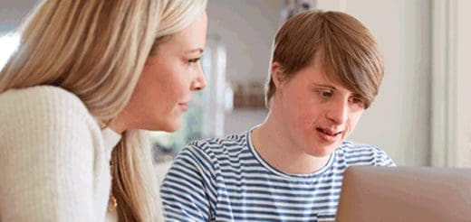 Woman and young man with Down syndrome looking at a laptop.