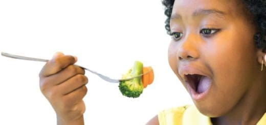Child eating broccoli and carrots on a fork
