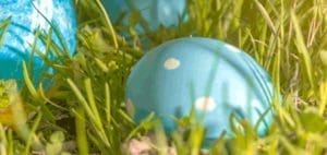 Two blue Easter eggs with white polka dots nestled in green grass.