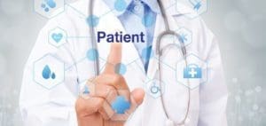 Doctor's hand touching the word "Patient" on a screen surrounded by medical icons.