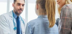 Doctor speaking with a girl and her mother.