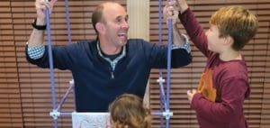 Greg Santucci demonstrates an occupational therapy activity with two children.