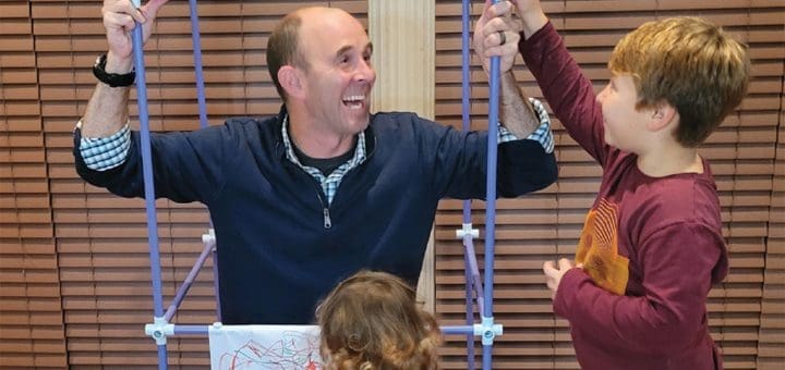 Greg Santucci demonstrates an occupational therapy activity with two children.