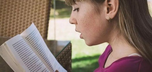 Young person reading a book outdoors.