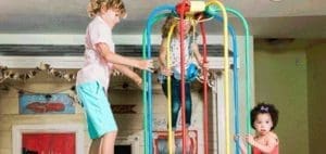 Three children play on a colorful jungle gym structure.