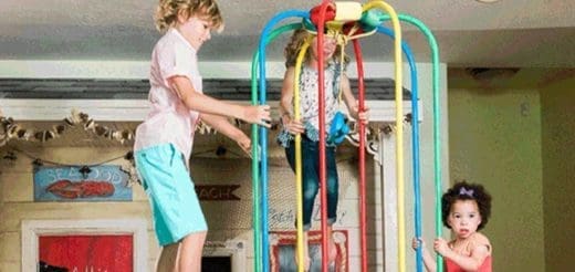Three children play on a colorful jungle gym structure.