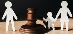Paper figures of parents and child with a gavel suggest a divorce case.