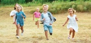 Children run across a field during a summer activity.