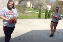 Two women holding balls and cups outdoors