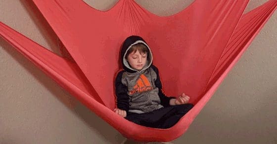 Boy sitting in a pink sensory swing.