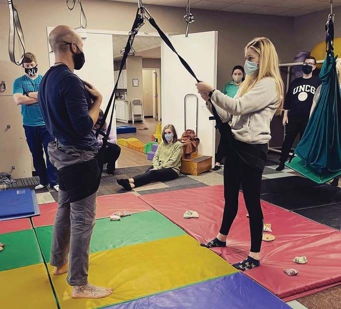 People in a sensory gym with hanging equipment and mats