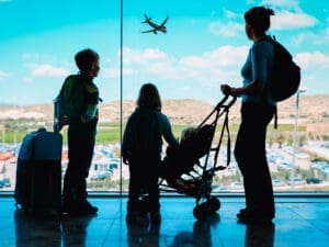 Family with luggage and stroller at an airport with a plane in the sky