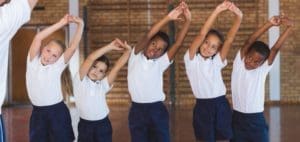 Children in gym class stretching with arms overhead