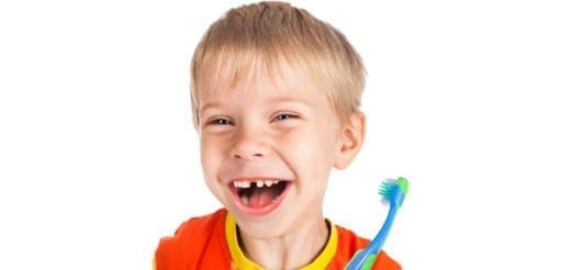 A smiling boy holds a toothbrush.
