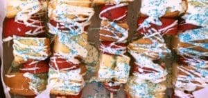 Fruit and donut skewers drizzled with white icing and blue sprinkles.