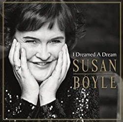 Susan Boyle smiling, hands on face, in front of album art for "I Dreamed A Dream.