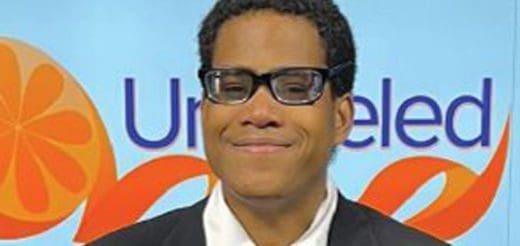 Thomas Wilson smiling wearing glasses with an orange and blue "Un-eled" logo behind him.
