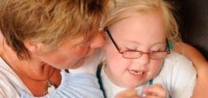 A child with glasses and a woman lean in together.