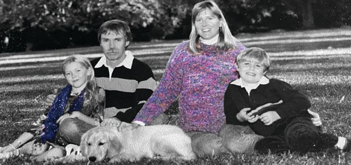 Family sitting together on the grass with their dog.
