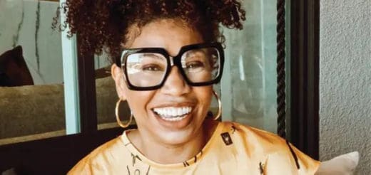 Dr. Cherina Williams smiles broadly while wearing large black-rimmed glasses.