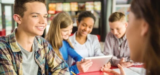 Students gathered around a tablet during a conversation.