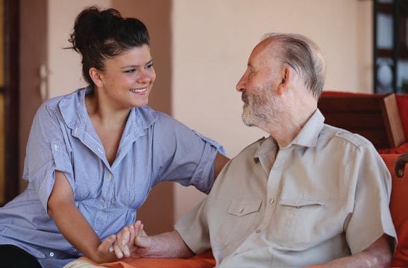 A young woman smiles while holding hands with an elderly man.